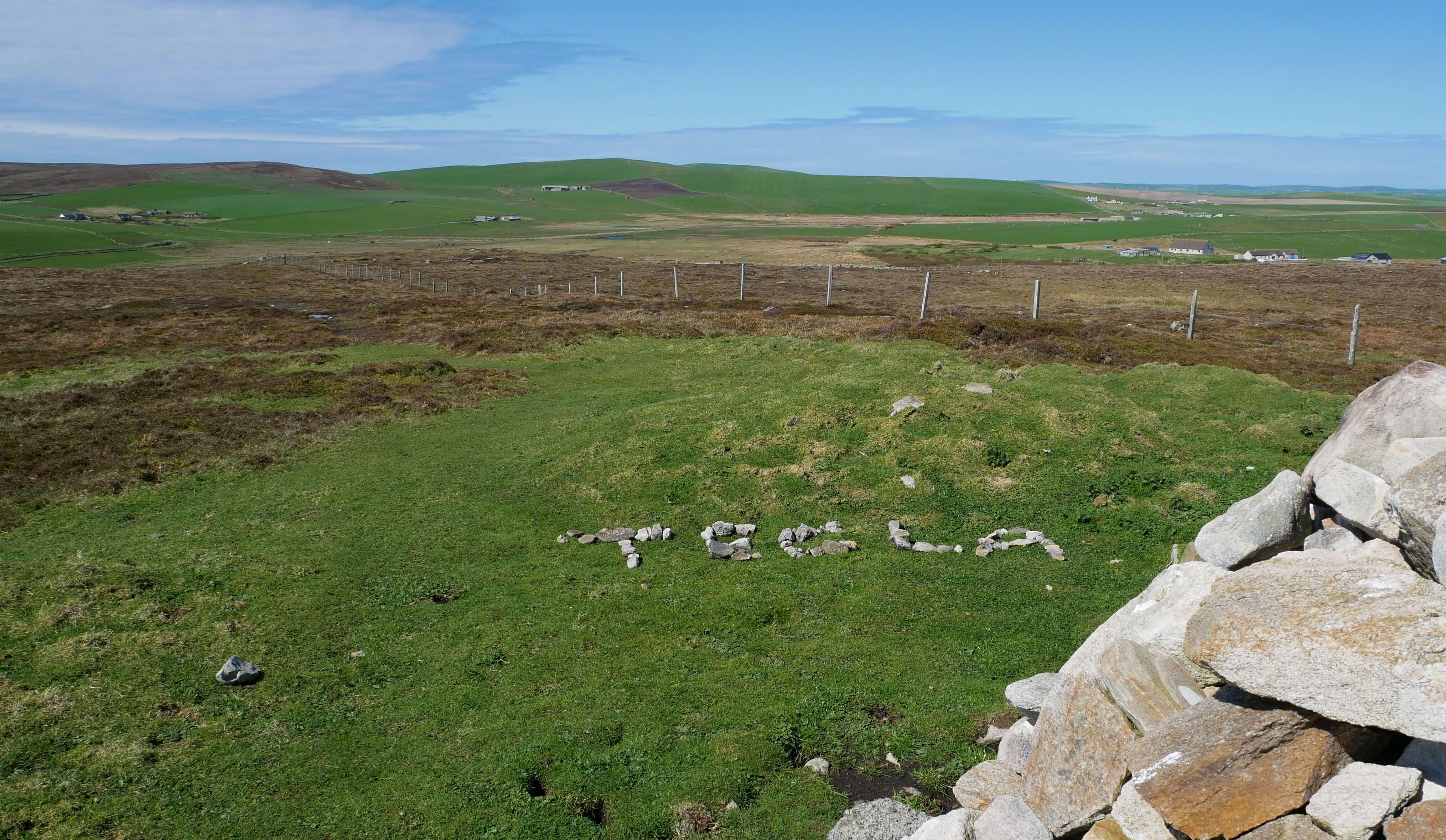 Visitors leave behind the name "Tecla", written in stone A name spelled out in stones on the brae, Stromness