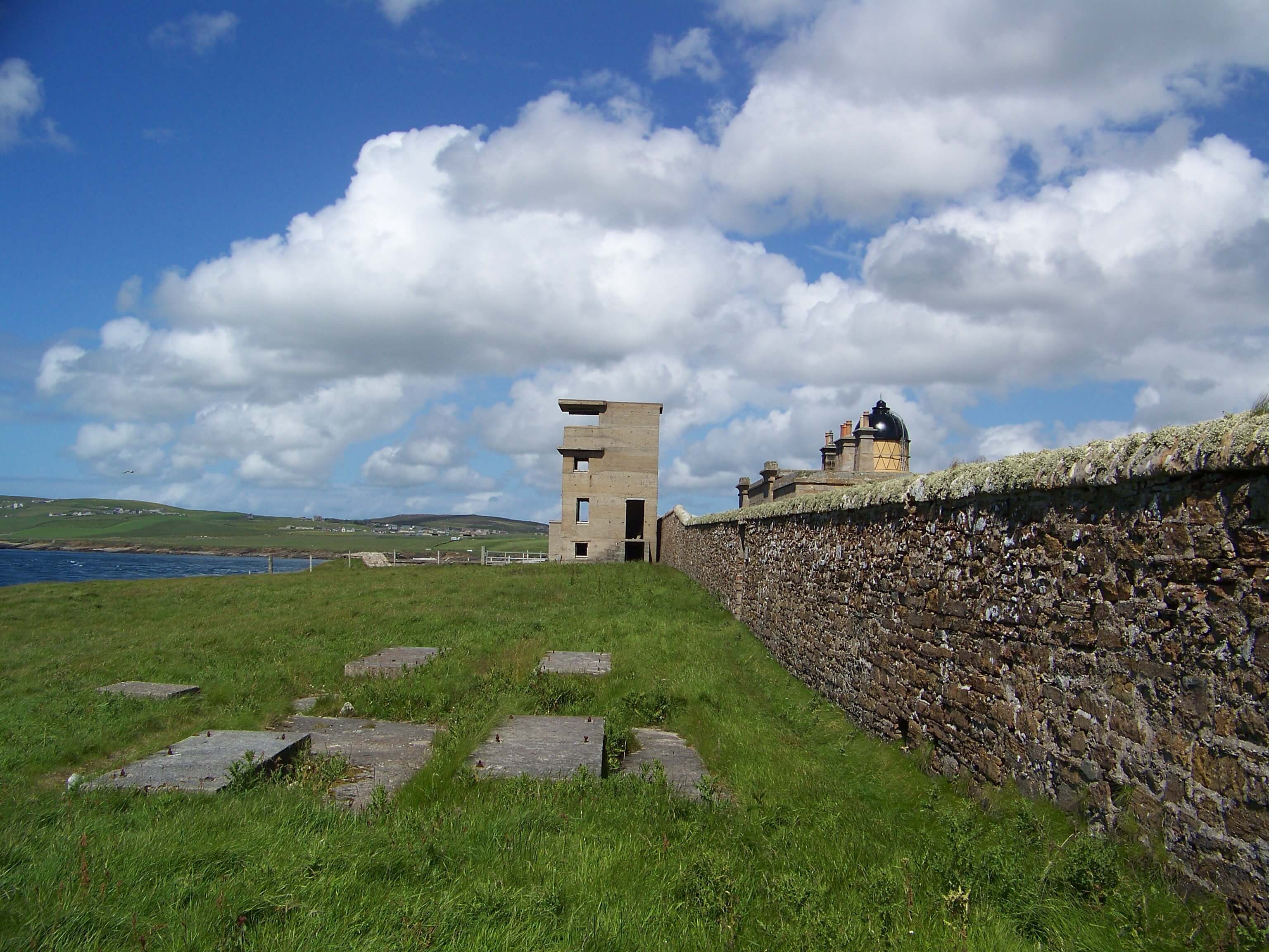 Graemsay Battery remains, with Hoy Low lighthouse behind Graemsay Battery and Hoy Sound Low lighthouse