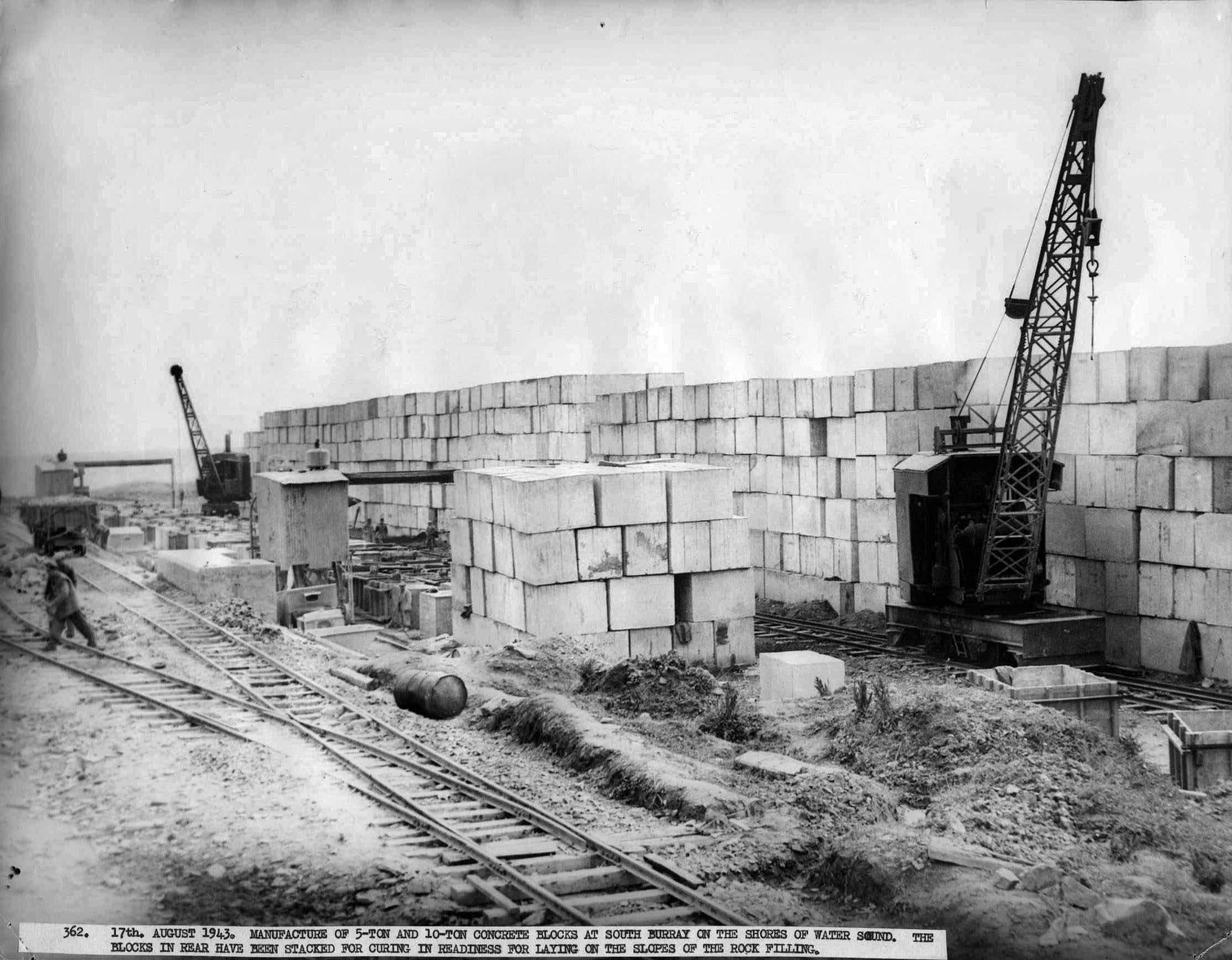 Manufacture of 5 and 10-ton concrete blocks at South Burray. The blocks have been stacked for curing in readiness for laying on the slopes of the rock filling. WWII Camp 34, Burray, Orkney Islands - pows build the Churchill Barriers. #Orkneyology.com