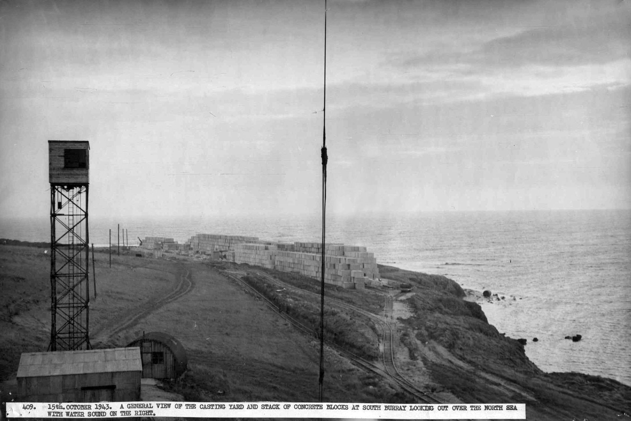 A general view of the casting yard and stack of concrete blocks at South Burray looking over the North Sea with Water Sound on the right. Building of the Churchill Barriers, WWII: A general view of the casting yard and stack of concrete blocks at South Burray looking over the North Sea with Water Sound on the right. #Orkneyology.com