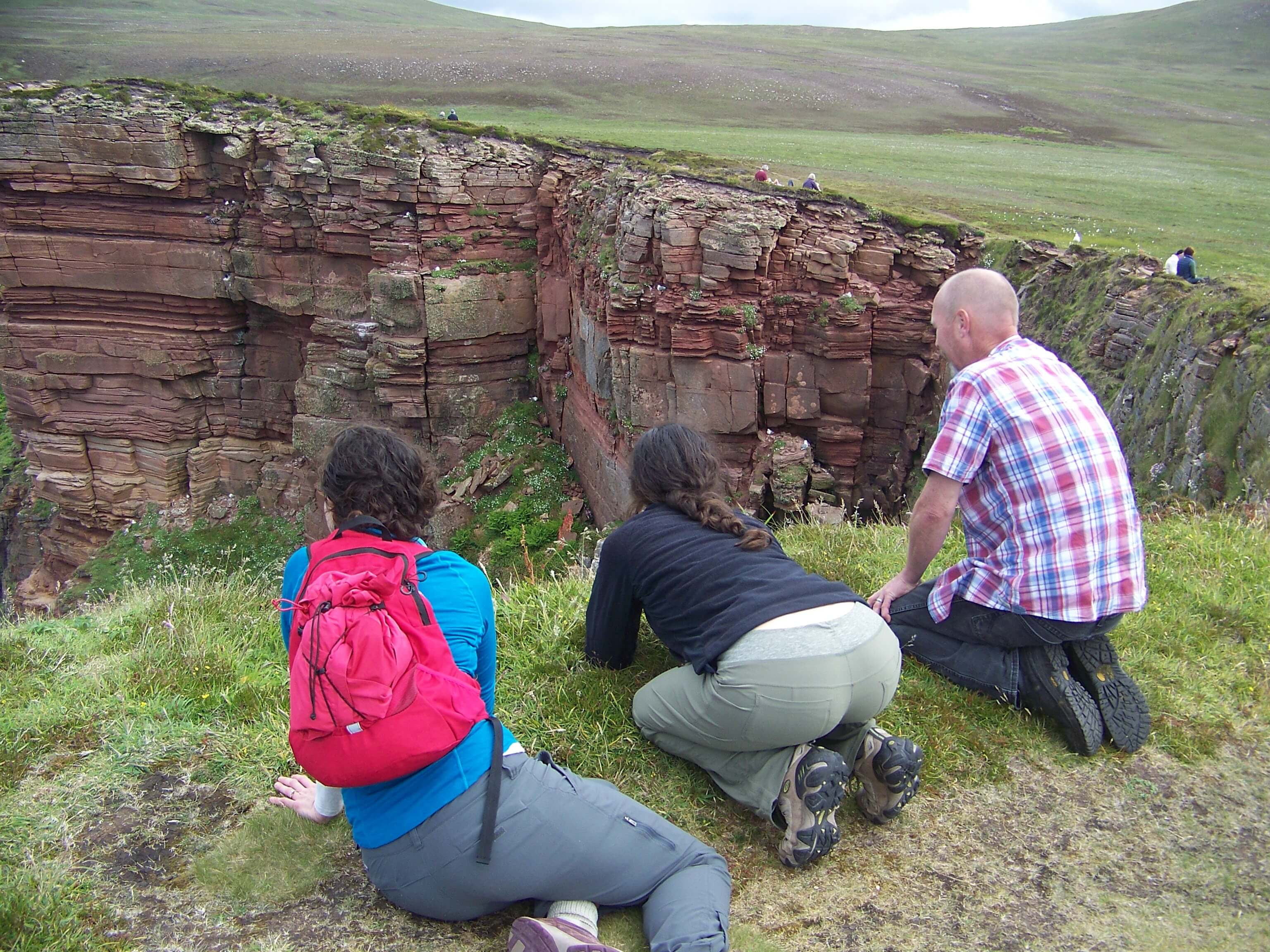Hikers looking for puffins on Orkney cliffs.