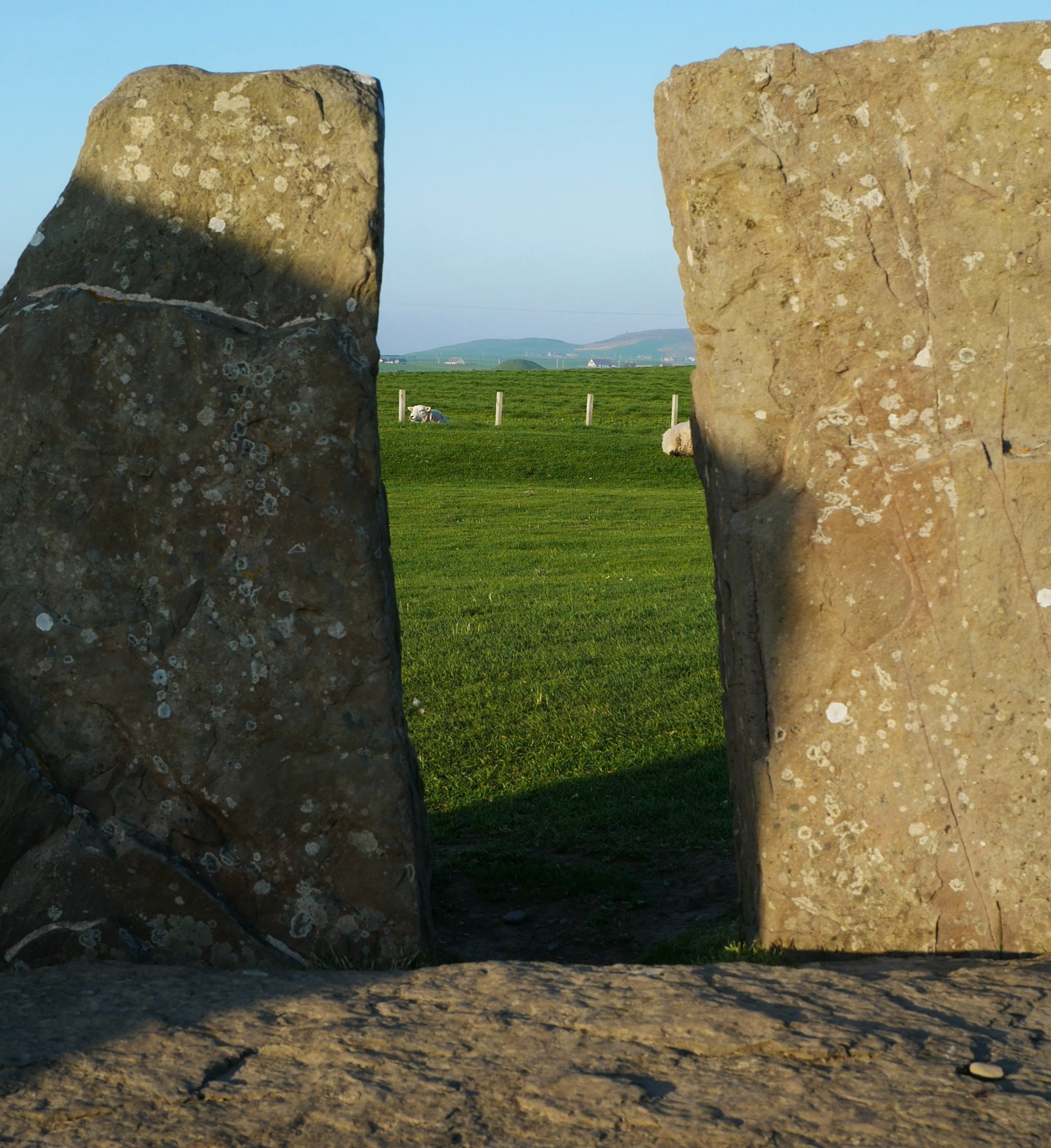 Maeshowe framed - the green hump in the distance Maeshowe Neolithic tomb framed between two standing stones of Stenness, Orkney Islands, Scotland, UK. Orkneyology.com